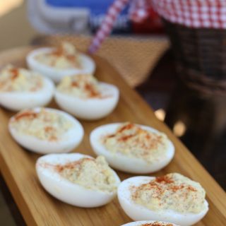 simple deviled eggs on a brown platter with eggs in the background