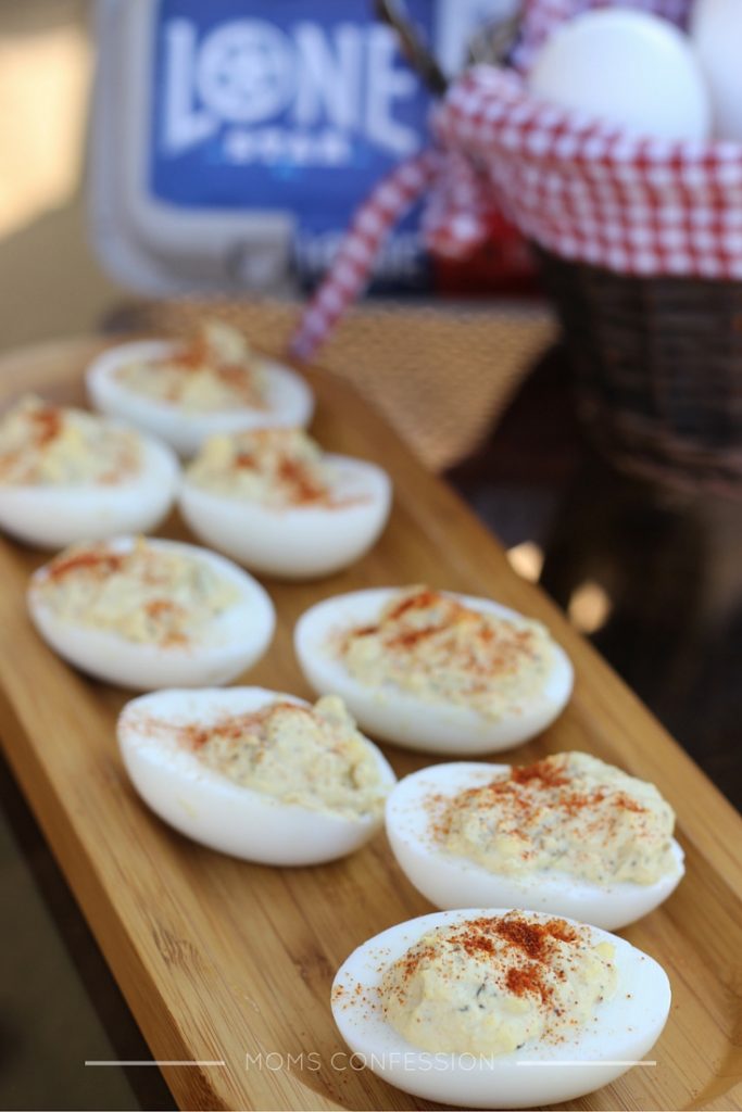 simple deviled eggs on a brown platter with eggs in the background