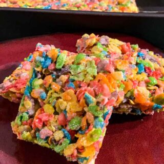 Fruity Pebble Rice Crispy Treats cut into squares on a red plate